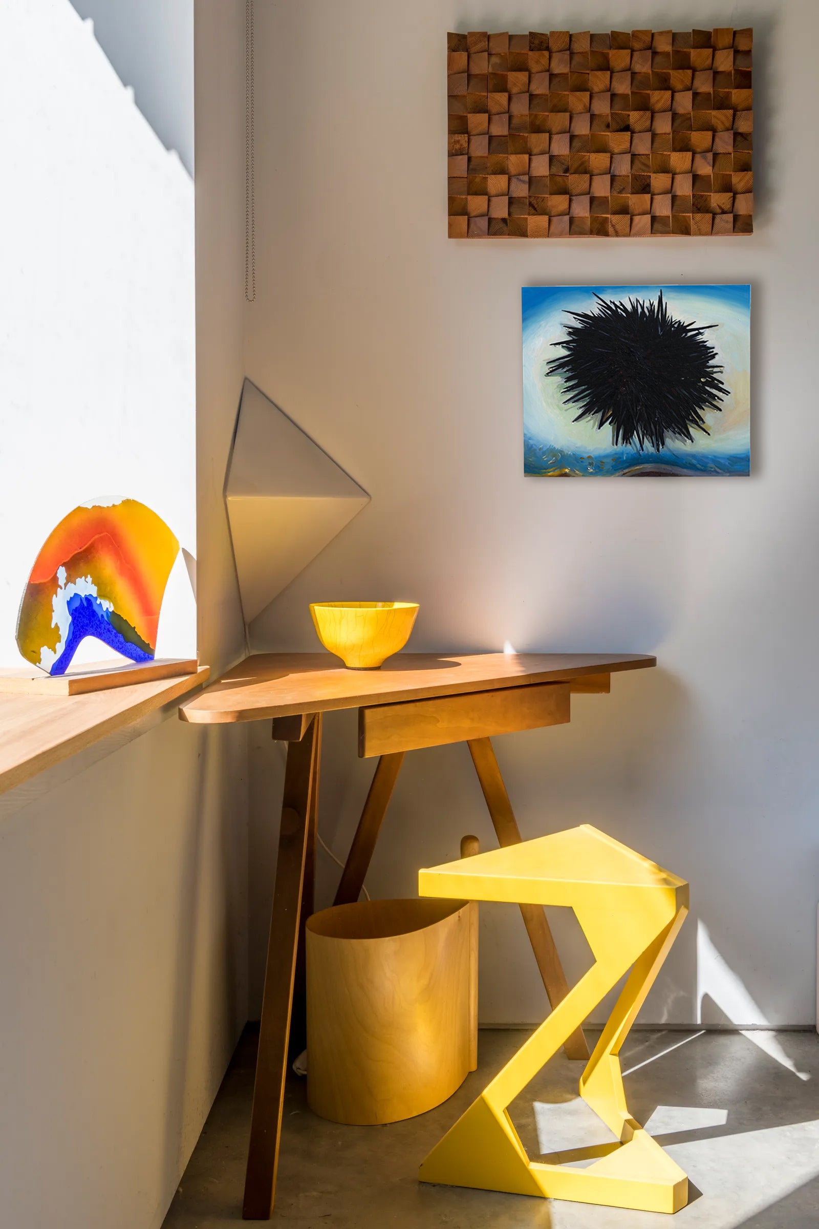 Modern interior with a wooden side table, colorful abstract art, and a yellow stool.