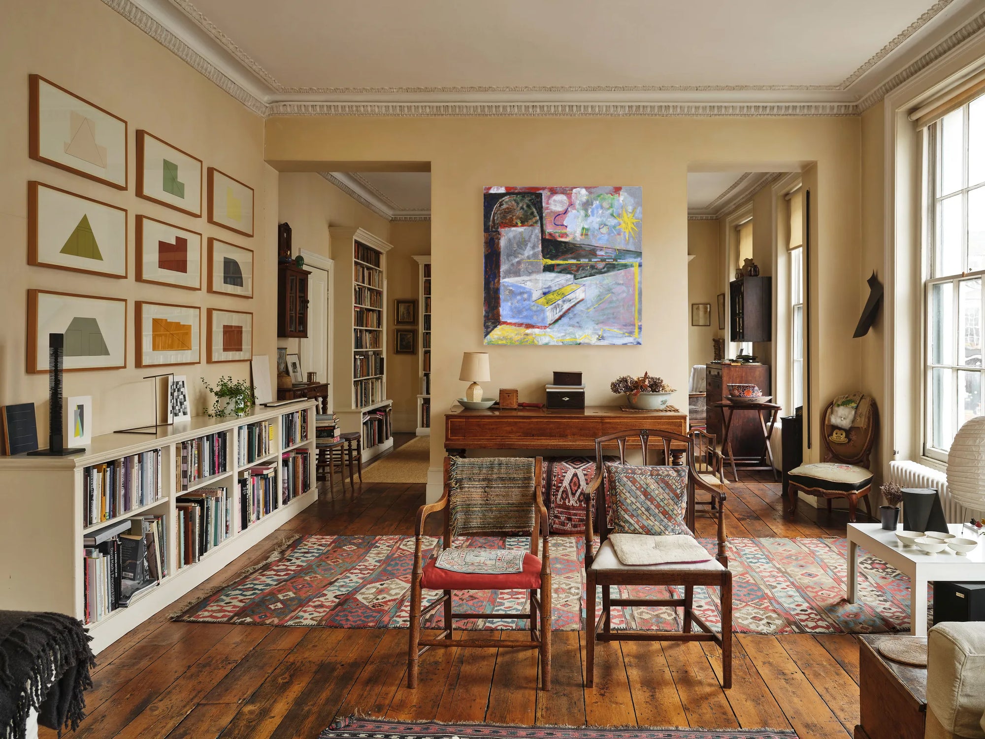 Living room with wooden floors, bookshelves, and a large painting on the wall.