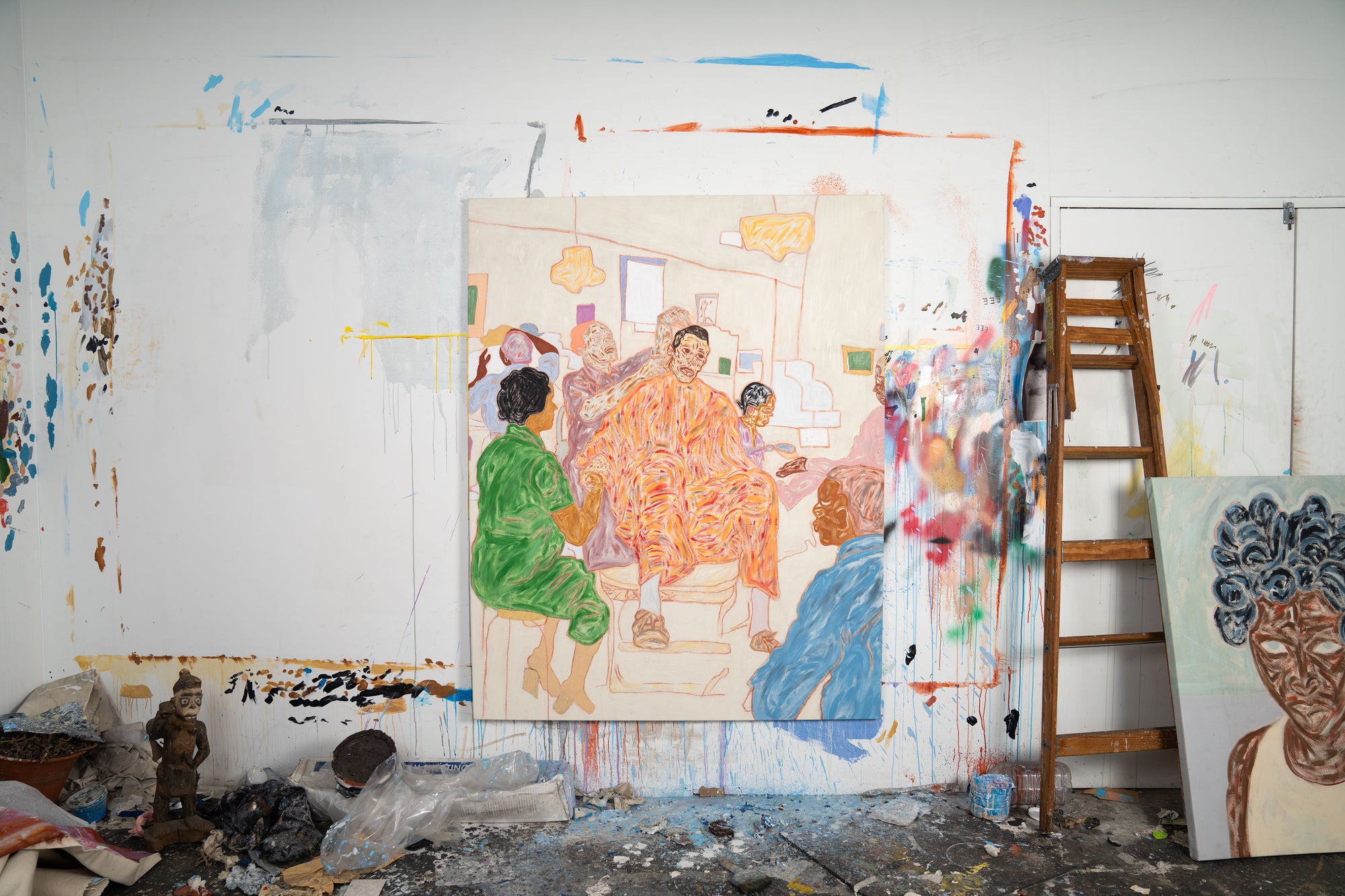 Art studio with a large painting of people and a ladder against a white wall.