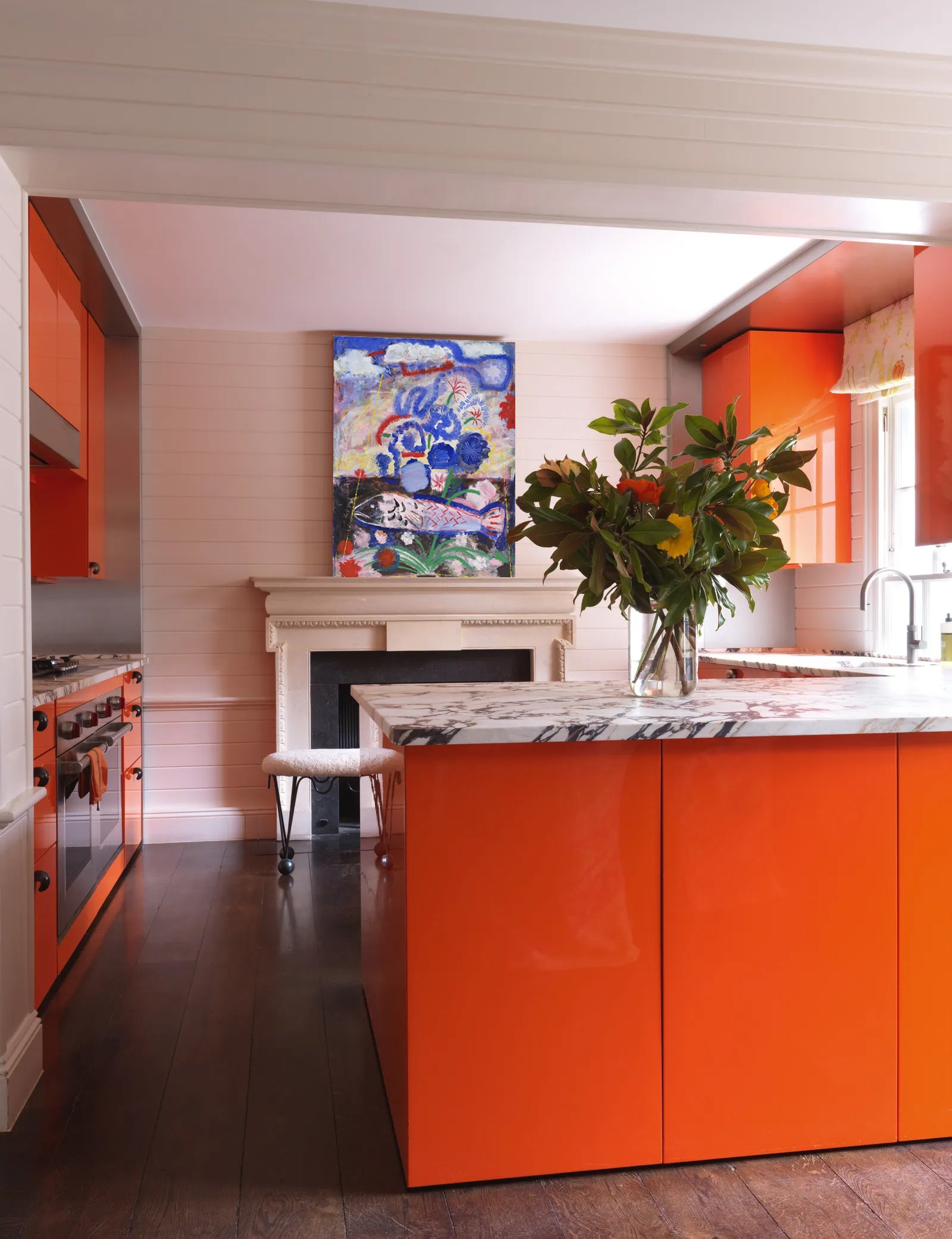 Modern kitchen with orange cabinets, a central island, and decorative elements.