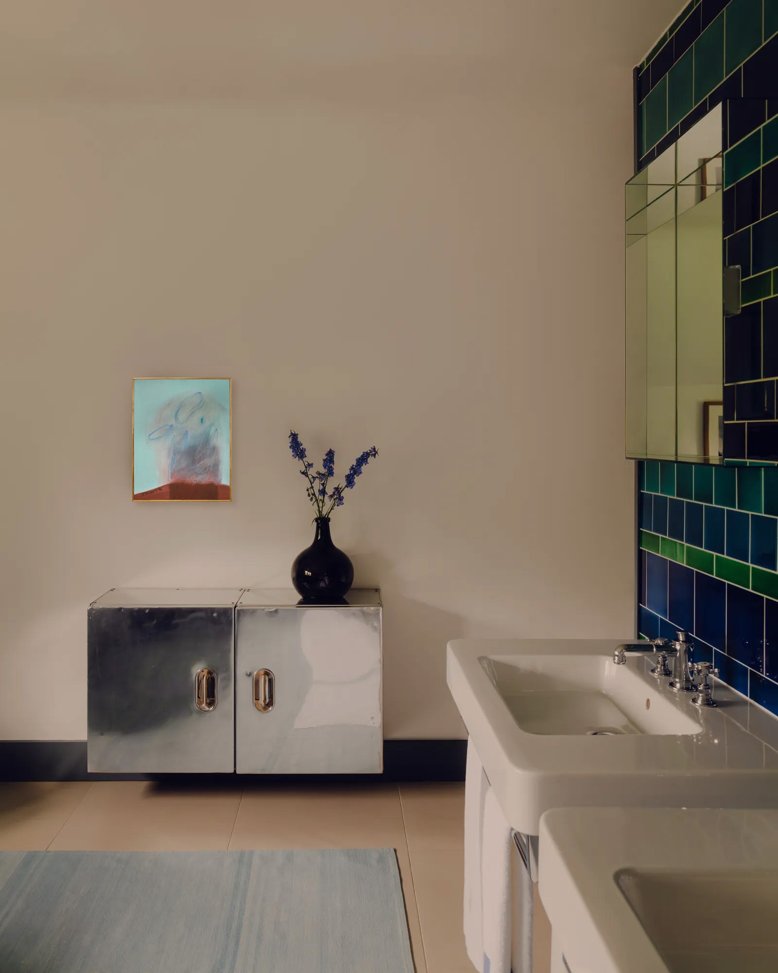 Bathroom interior with a mirror, sink, and decorative vase on a cabinet.
