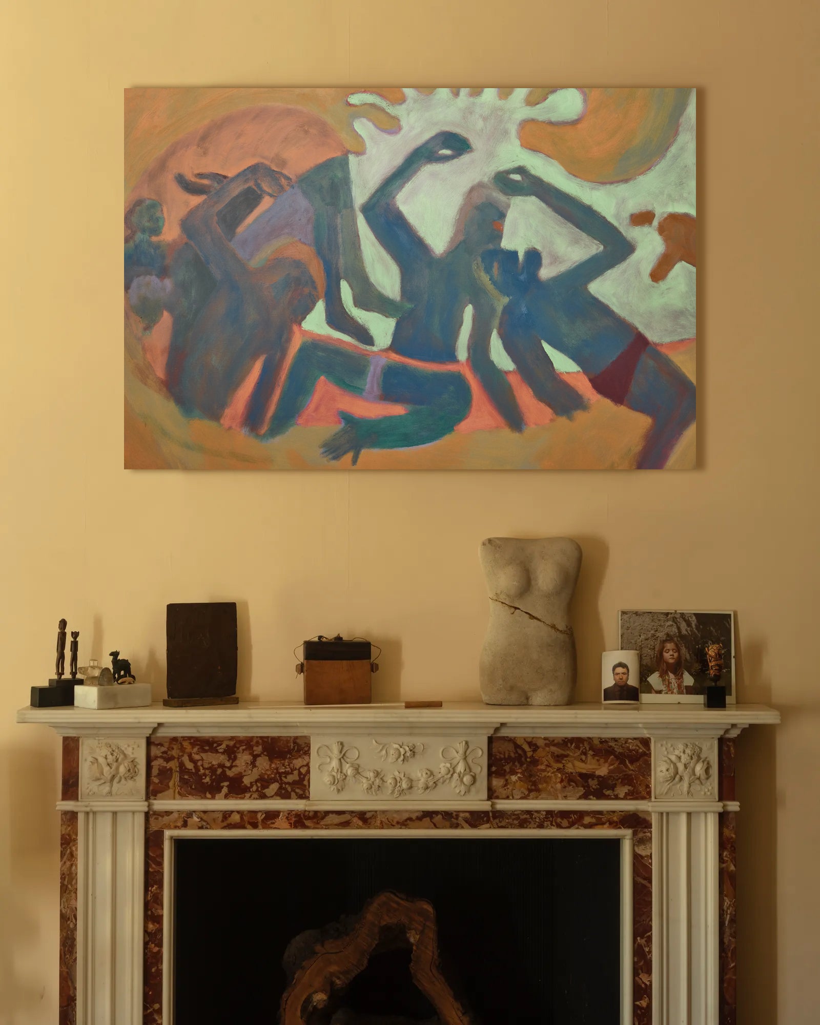 Abstract painting above a fireplace with decorative items